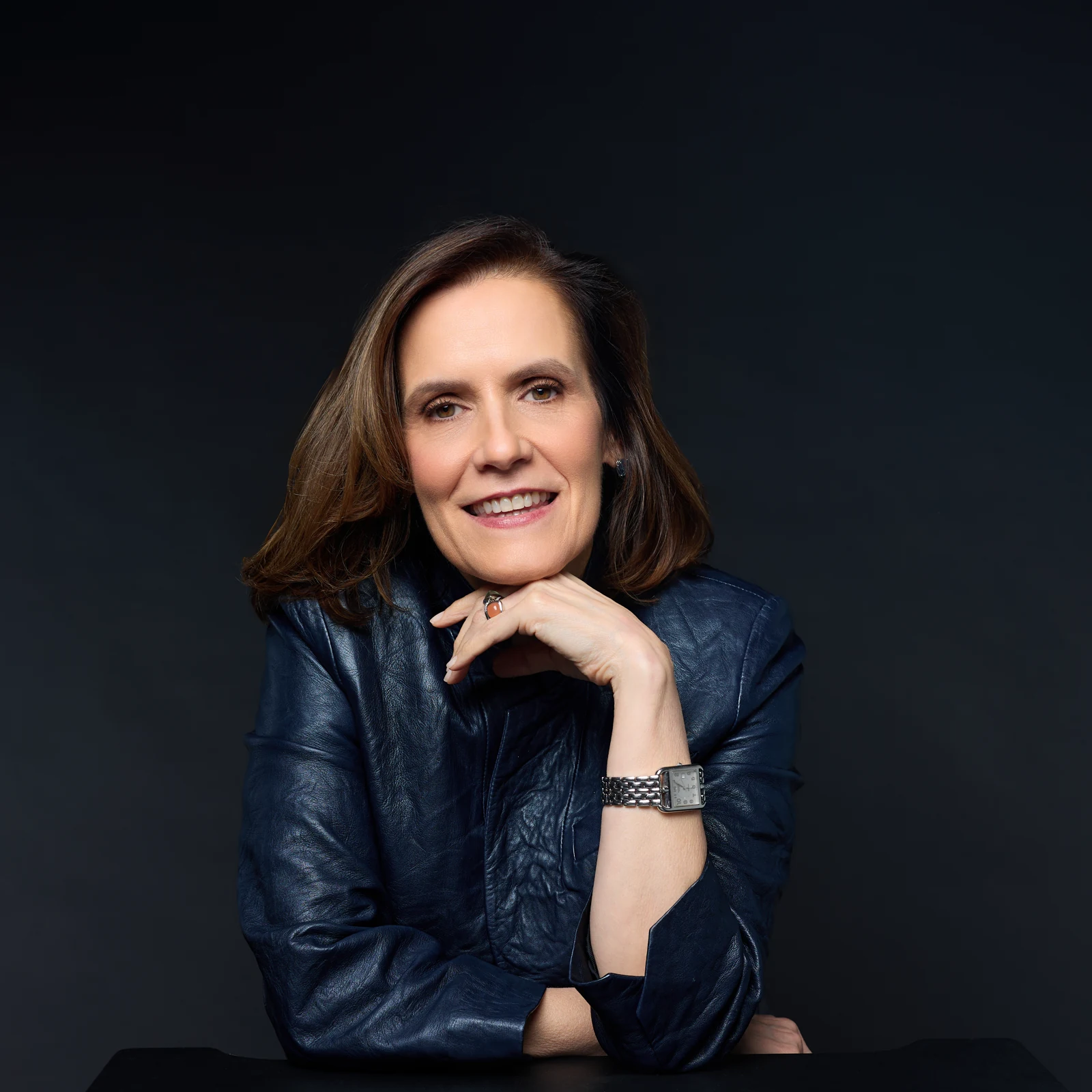 Gabriela Pulido leaning forward in a navy jacket