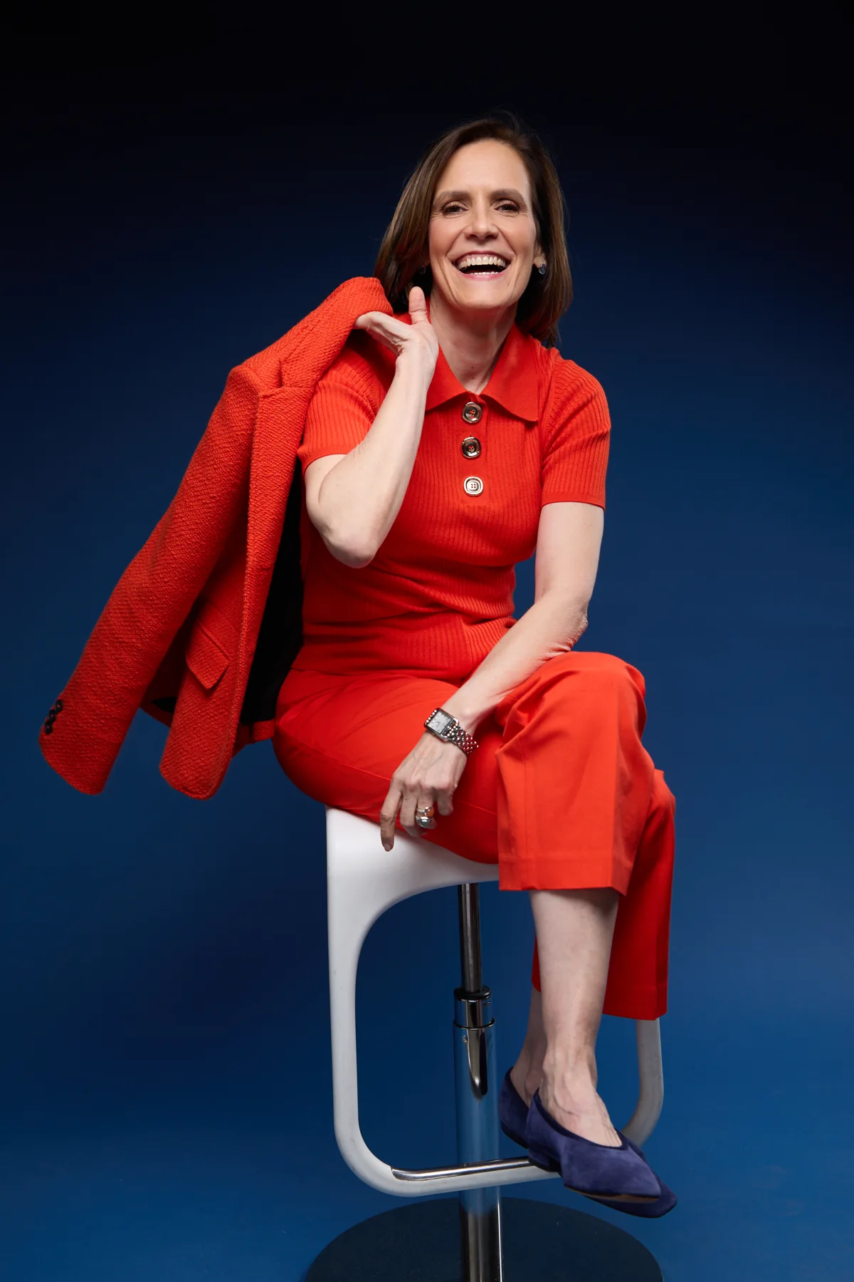 Gabriela Pulido seated in a red outfit against a dark blue background